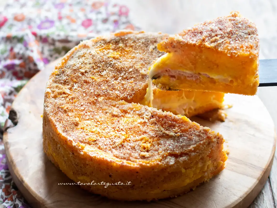 Una fetta di zucca al forno, soffice e dorata, con strati di formaggio e prosciutto, pronta per essere gustata.