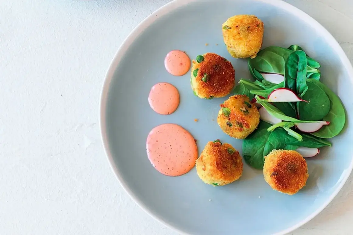 Deliziose polpette di verdure dorate, servite con insalata fresca e salsa rosa su un piatto azzurro.