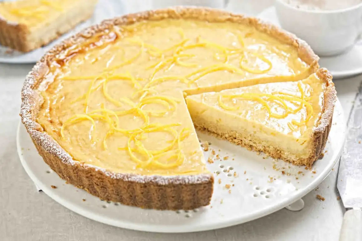 Una deliziosa crostata con crema pasticcera, guarnita con scorza di limone e spolverata di zucchero a velo.