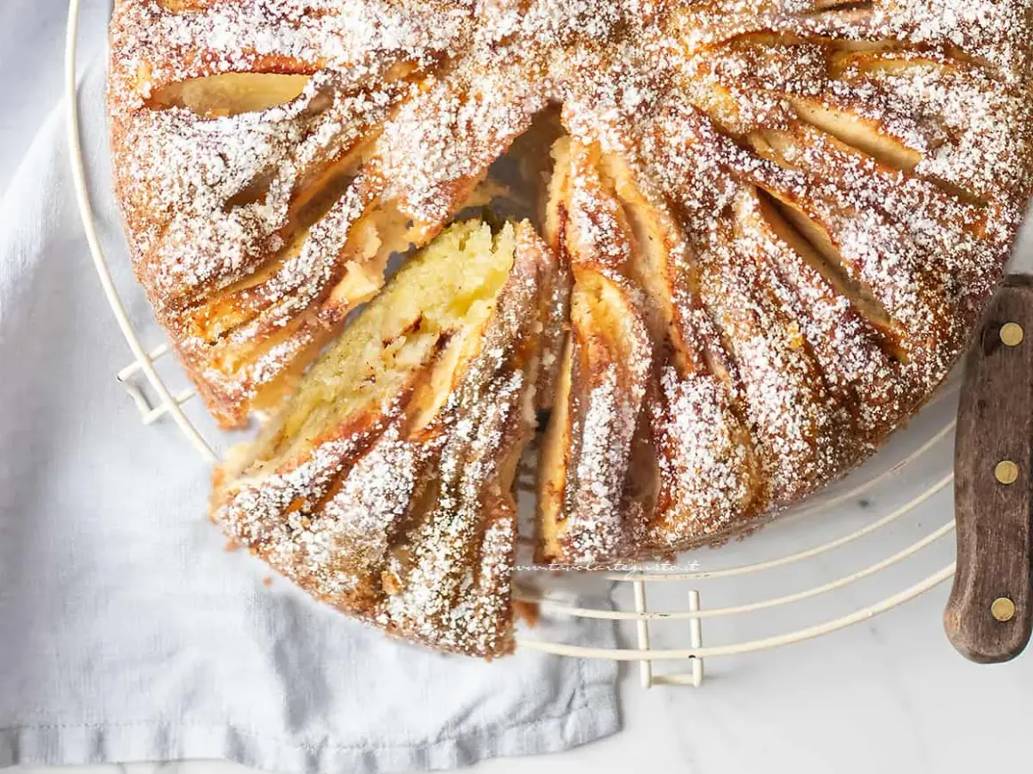 Deliziosa torta di mele in friggitrice ad aria, cosparsa di zucchero a velo, con una fetta tagliata che rivela il morbido interno.