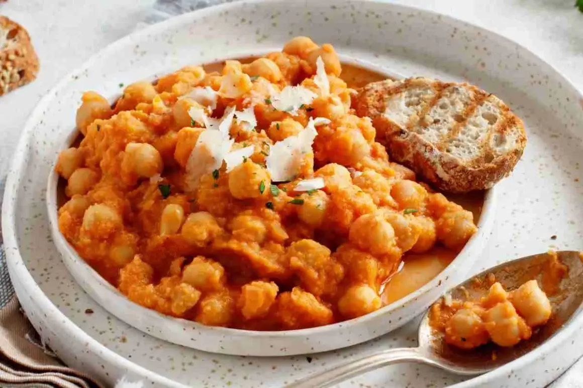 Minestra di ceci cremosa e saporita, guarnita con scaglie di parmigiano e accompagnata da pane tostato.