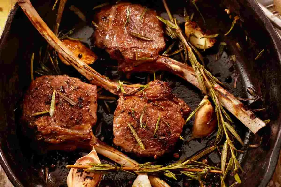Tre succulenti costolette di agnello in padella, condite con rosmarino e aglio, pronte per essere gustate.