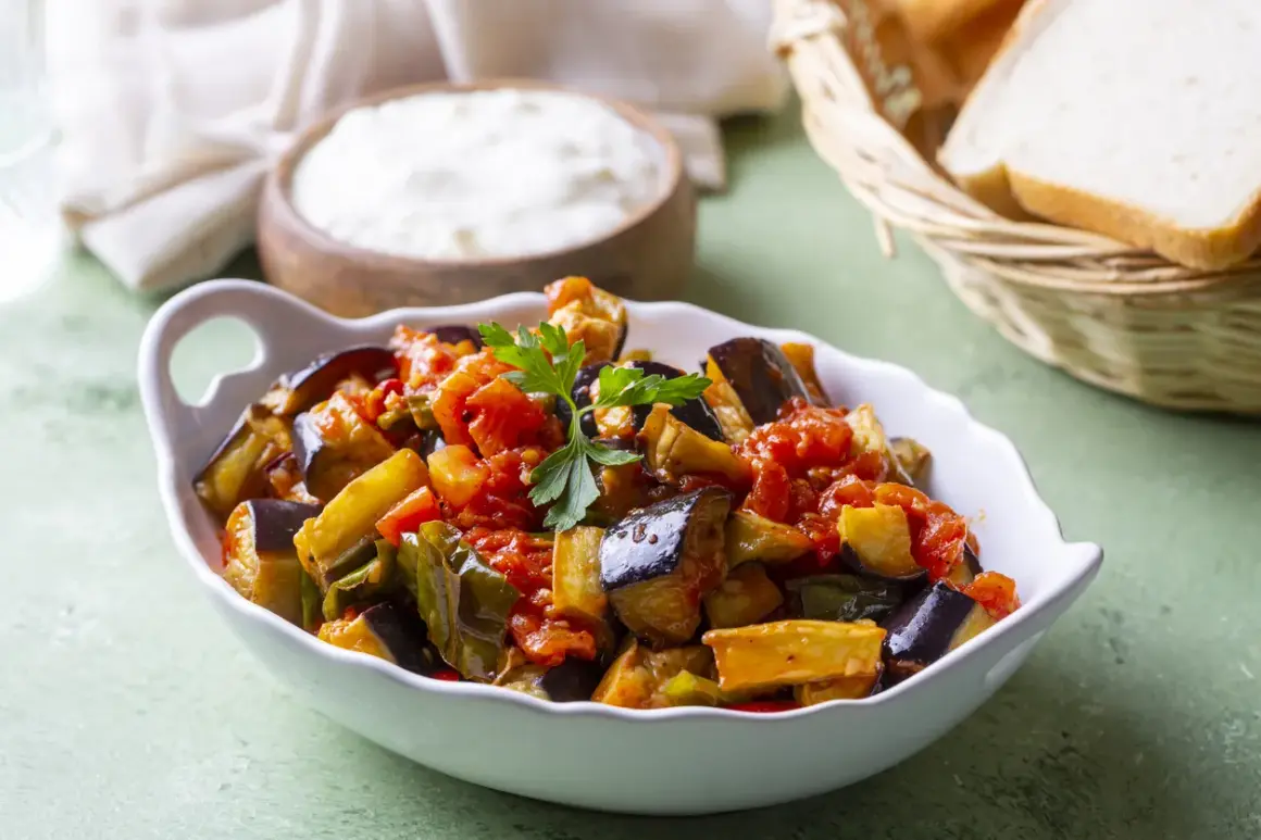 Melanzane al funghetto non fritte, un contorno saporito e leggero, servito in una ciotola bianca con pane e formaggio sullo sfondo.