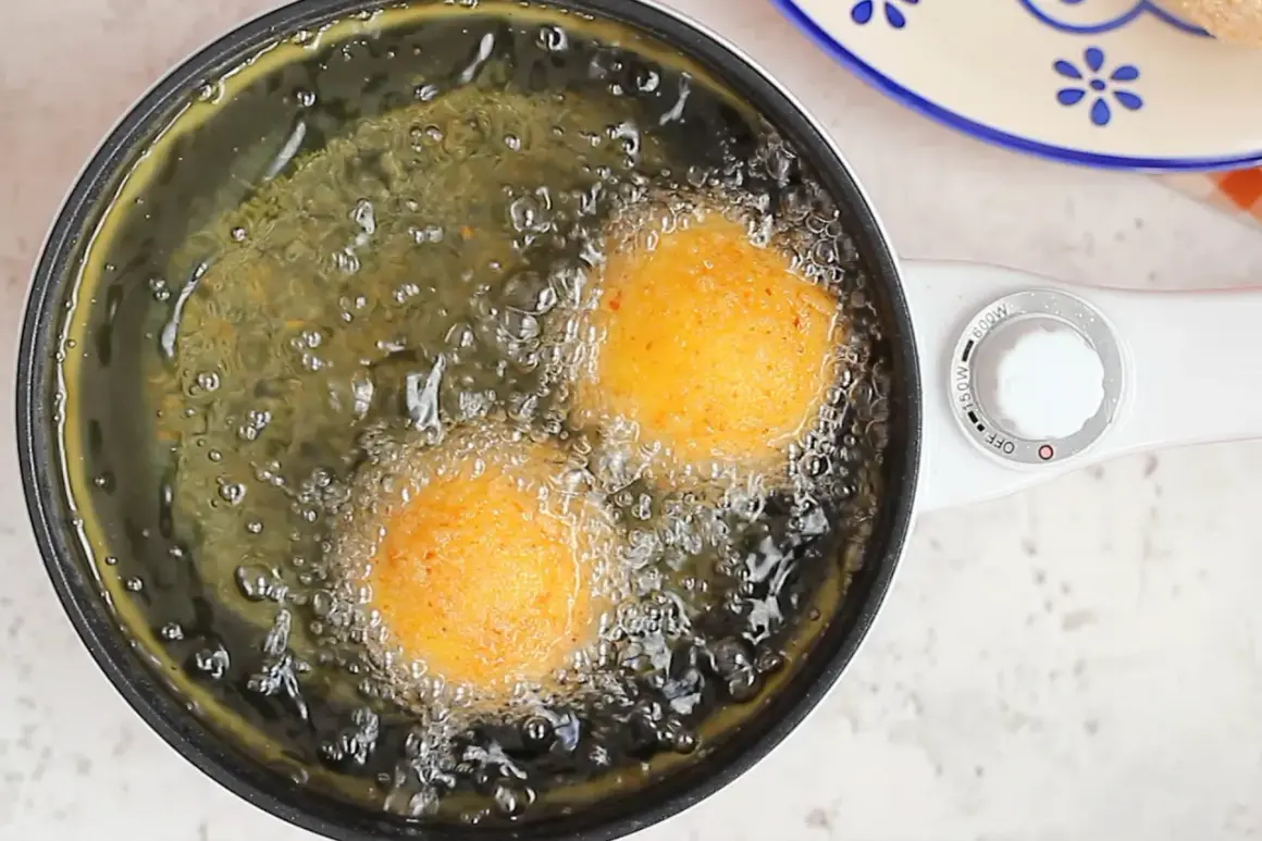Arancini di riso dorati friggono nell'olio bollente, creando un profumo invitante.