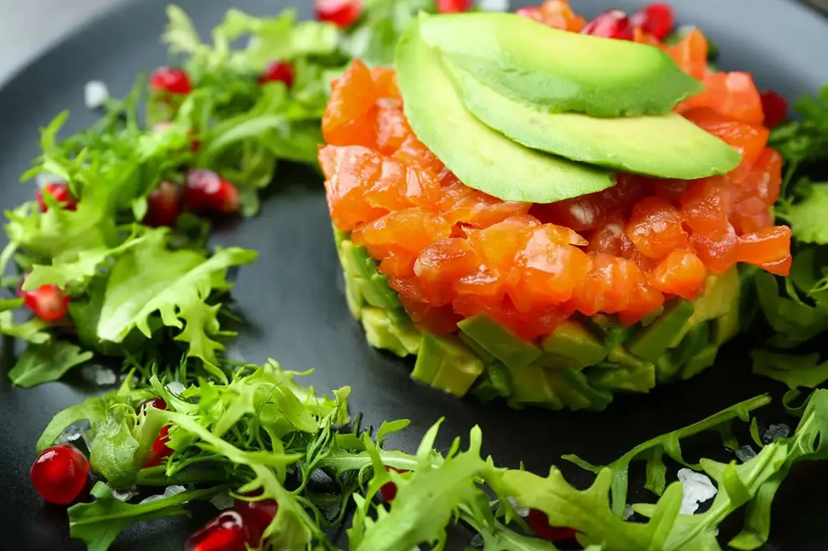 Tartare di salmone e avocado, guarnita con melagrana e insalatina fresca. Antipasti sfiziosi per stupire con gusto e colore.