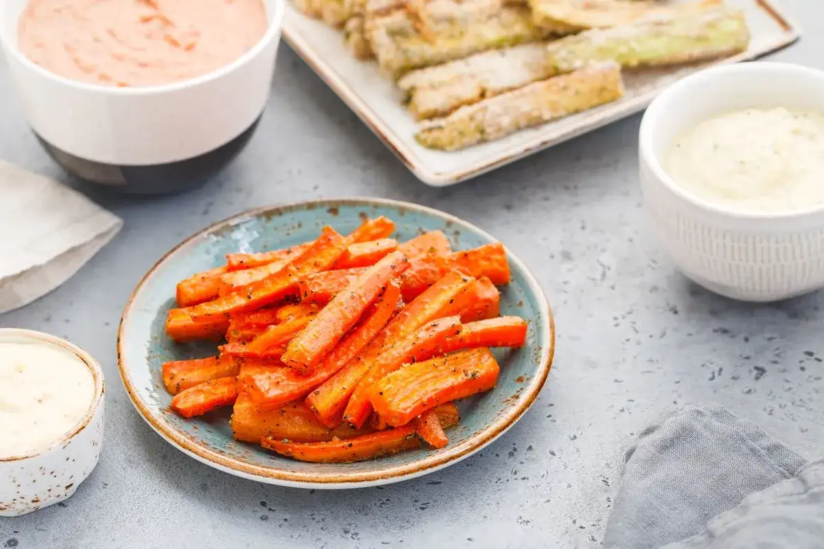 Carote al forno croccanti e saporite, servite con salse cremose. Un contorno perfetto per ogni pasto.