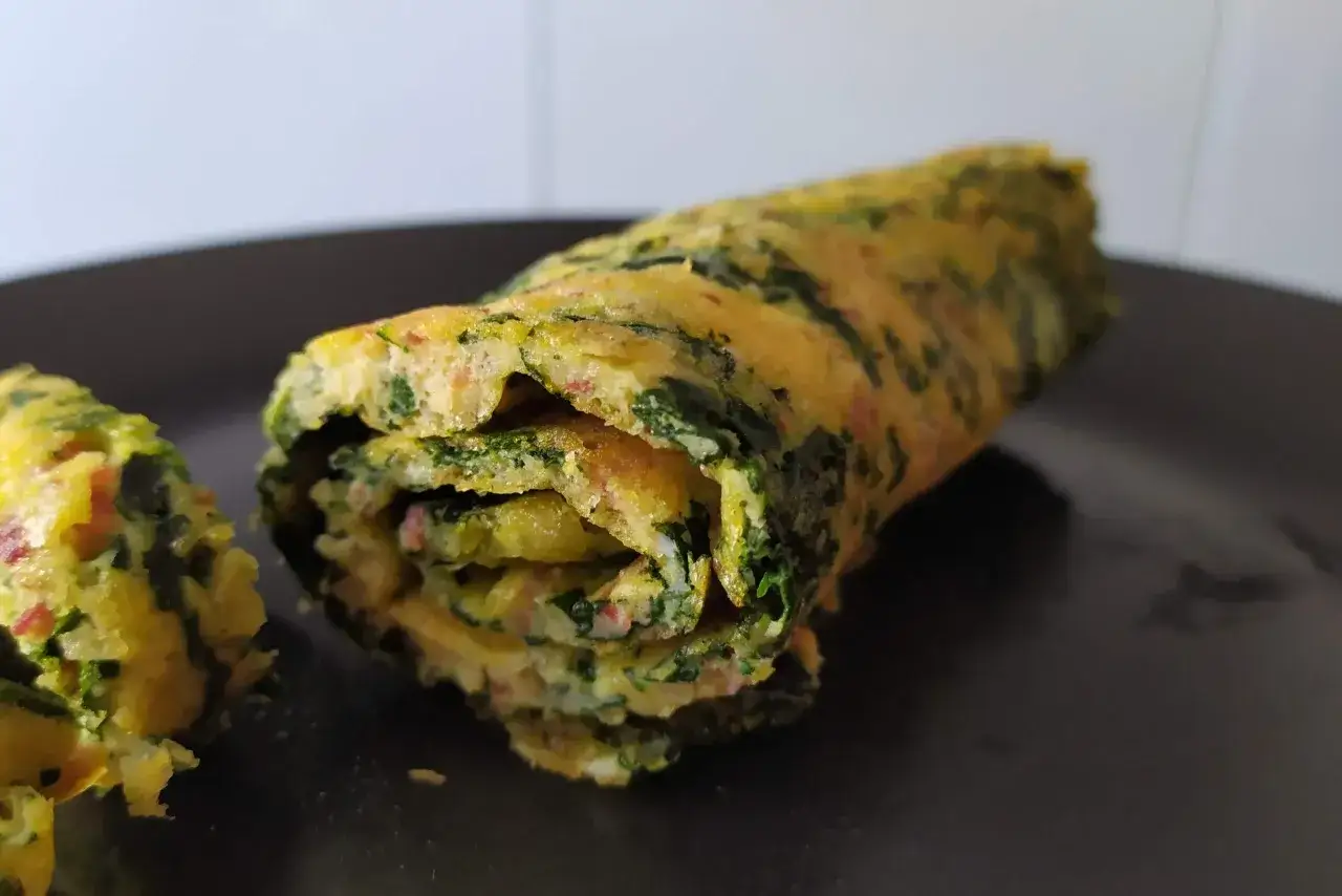 Rotolo di frittata di spinaci, un piatto gustoso e colorato, pronto per essere gustato.