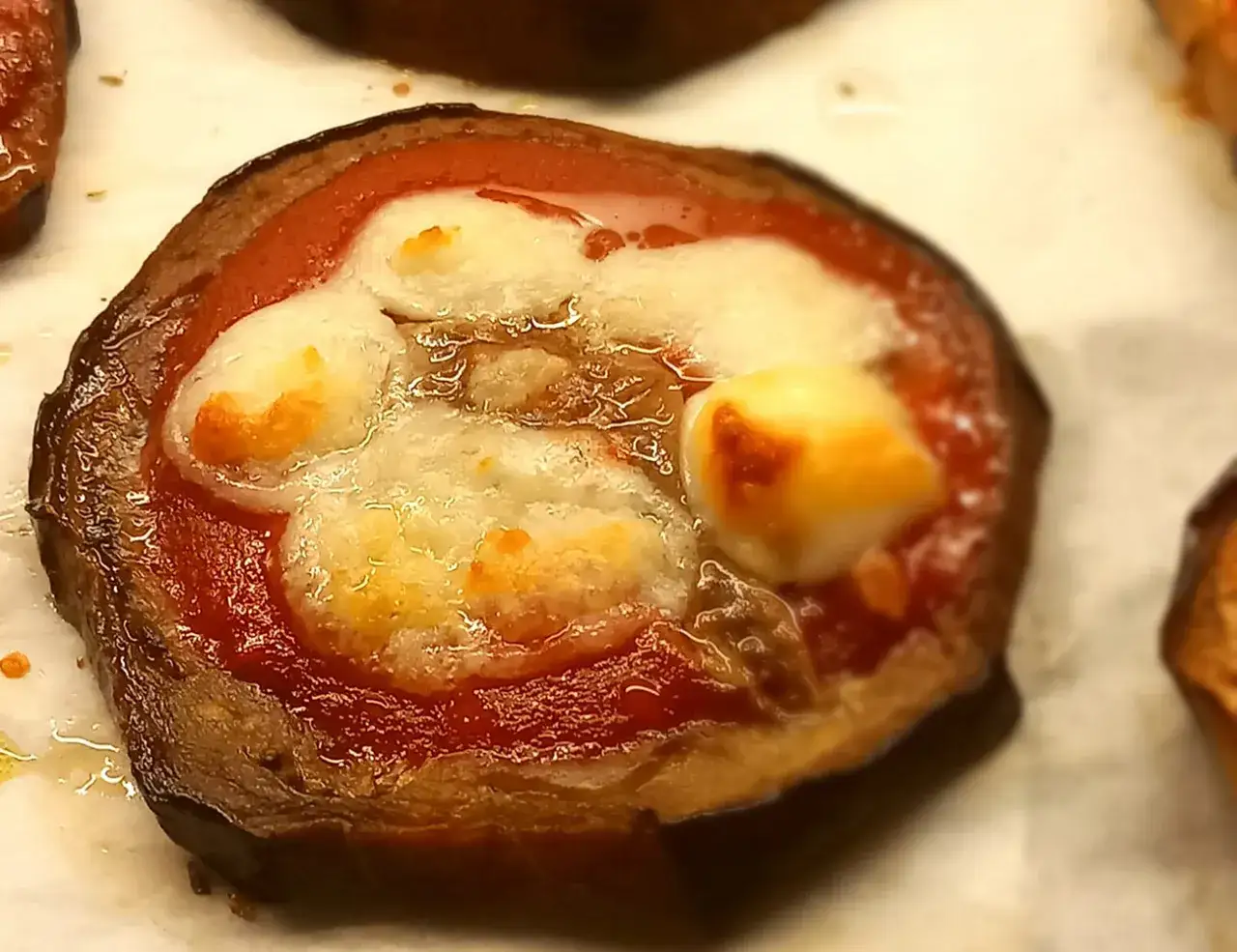 Pizzette di melanzane con pomodoro e mozzarella filante, un antipasto sfizioso e leggero.