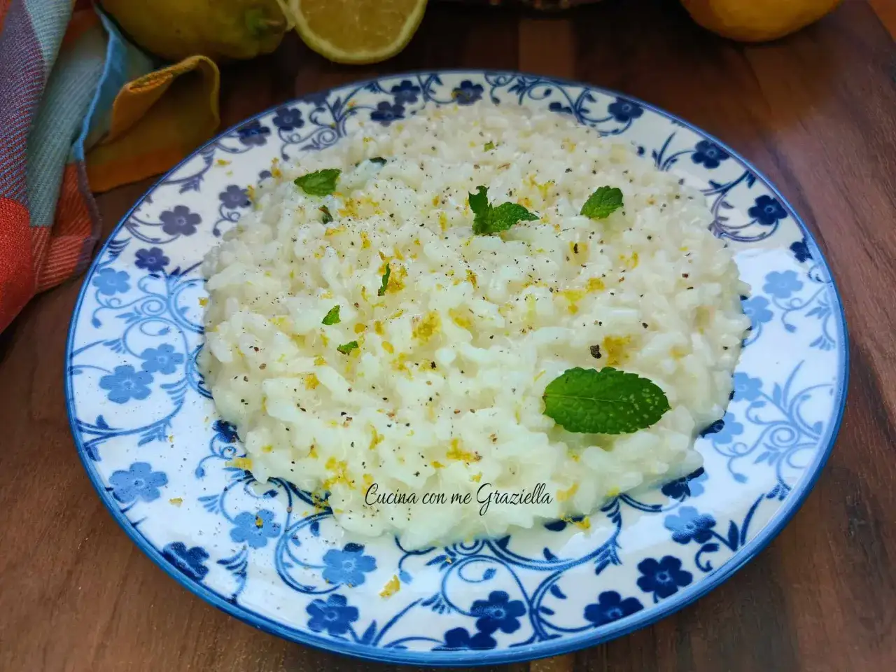 Un cremoso risotto al limone, guarnito con scorza di limone, pepe nero e foglie di menta fresca.