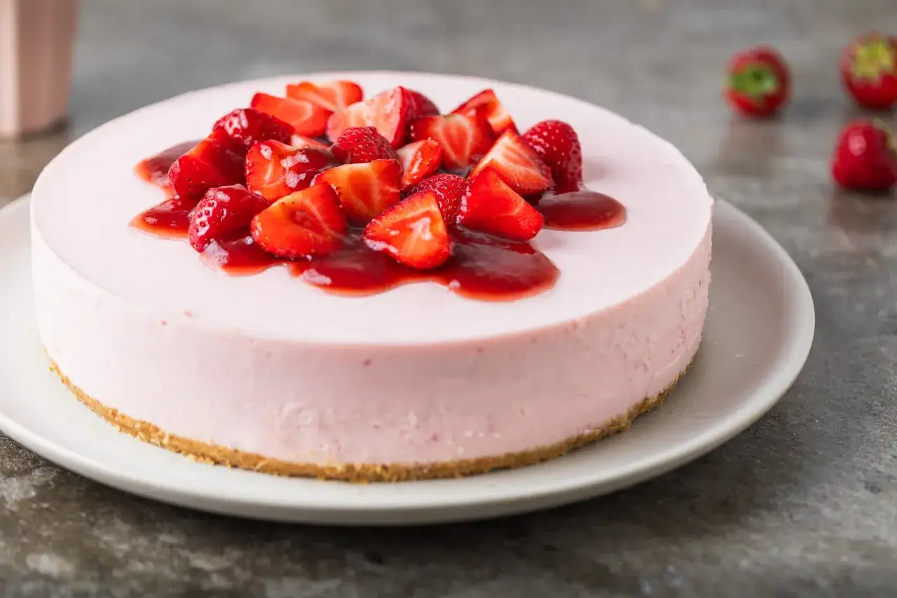 Delizioso cheesecake alle fragole, con una copertura di fragole fresche e salsa rossa, su una base croccante.