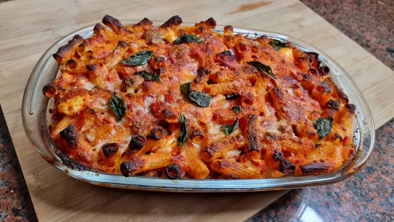 Un invitante pasta al forno, dorata e filante, con pomodoro e basilico fresco, pronta per essere gustata.
