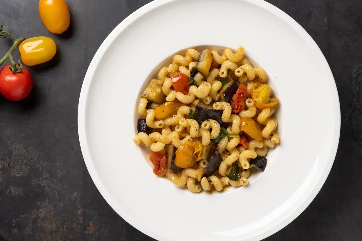 Piatto di pasta con melanzane e pomodorini, un classico saporito.