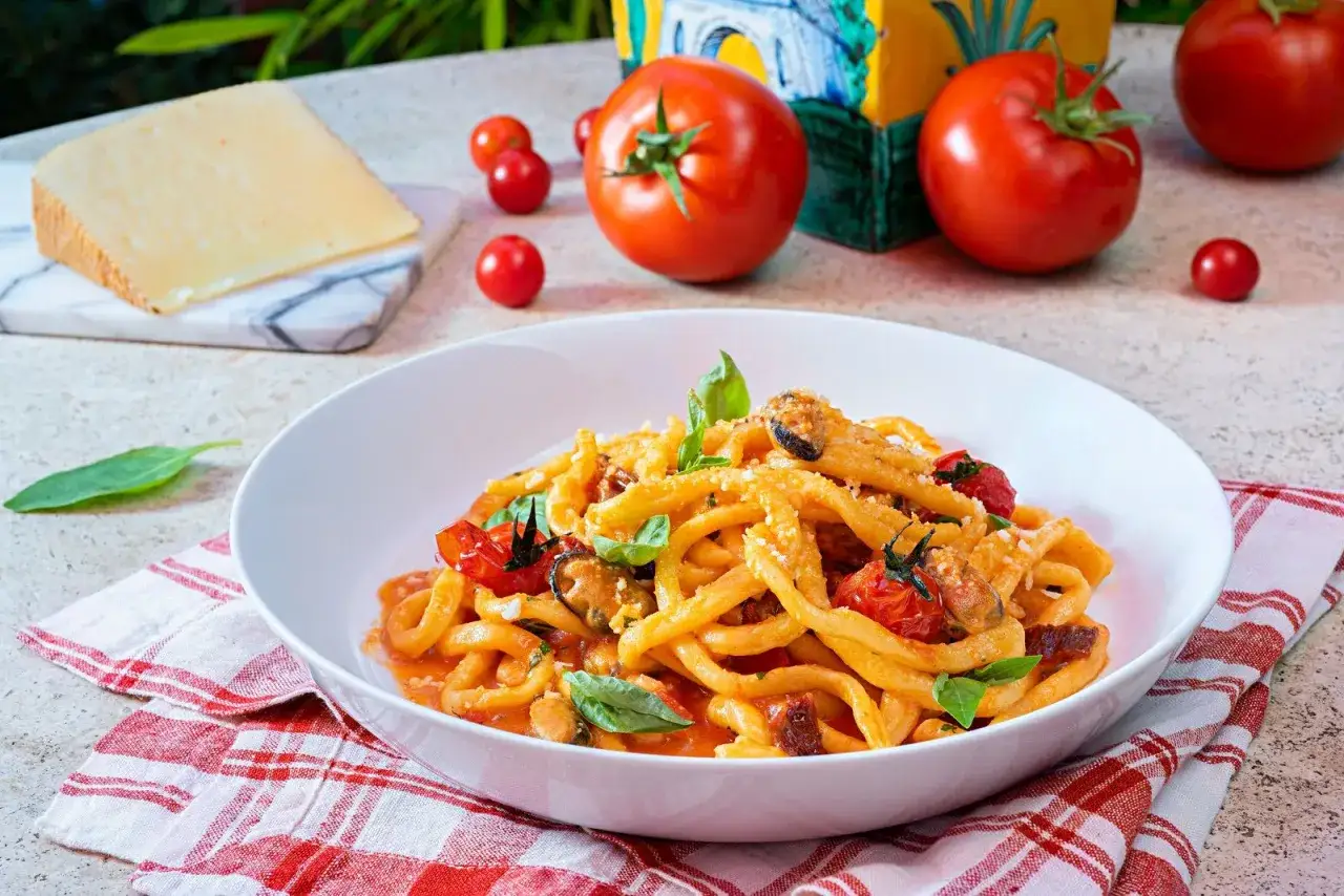 Un piatto invitante di pasta con pomodorini freschi, cozze e basilico, pronto per essere gustato.