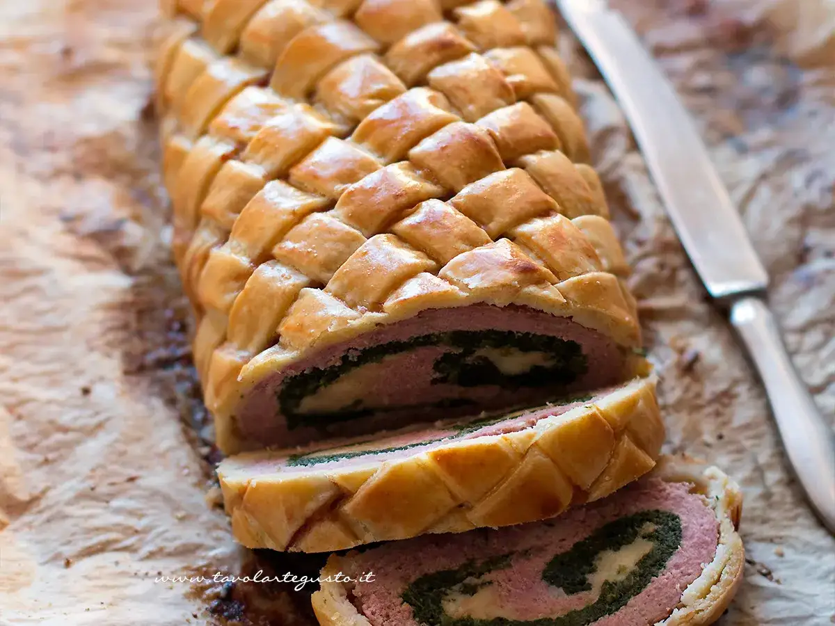 Un delizioso polpettone in crosta, con un ripieno di carne, spinaci e formaggio, pronto per essere affettato.