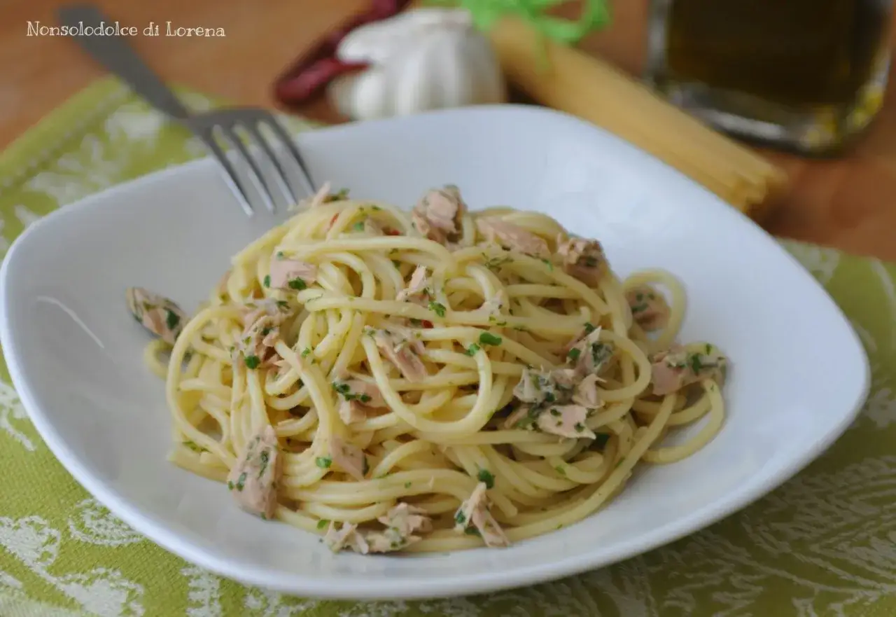 Un piatto di spaghetti con tonno e limone, conditi con prezzemolo fresco e un filo d'olio.