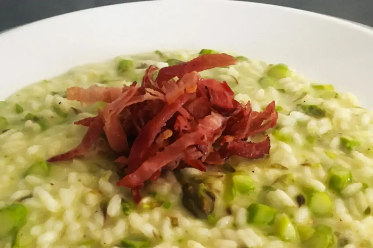 Risotto cremoso con asparagi e speck croccante, un piatto primaverile che delizia il palato.