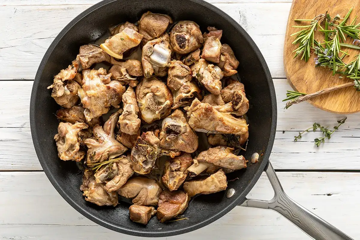 Succulento agnello in padella, dorato e profumato con erbe aromatiche. Un piatto invitante pronto per essere gustato.