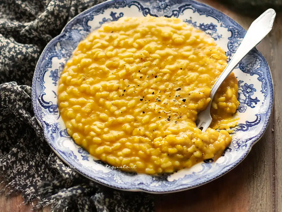 Un invitante risotto con la zucca cremoso, servito su un piatto decorato, con una forchetta che ne assaggia la morbidezza.