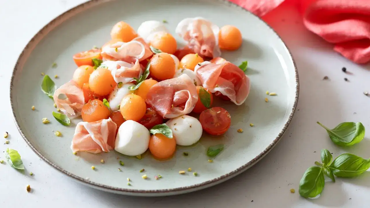 Delizioso piatto di prosciutto e melone con mozzarelline, pomodorini e basilico.