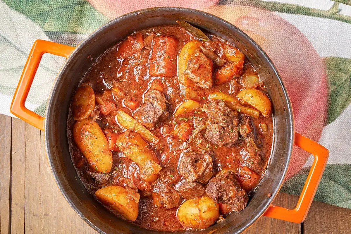 Un invitante spezzatino di vitello cotto lentamente in una casseruola con patate e carote, pronto per essere gustato.
