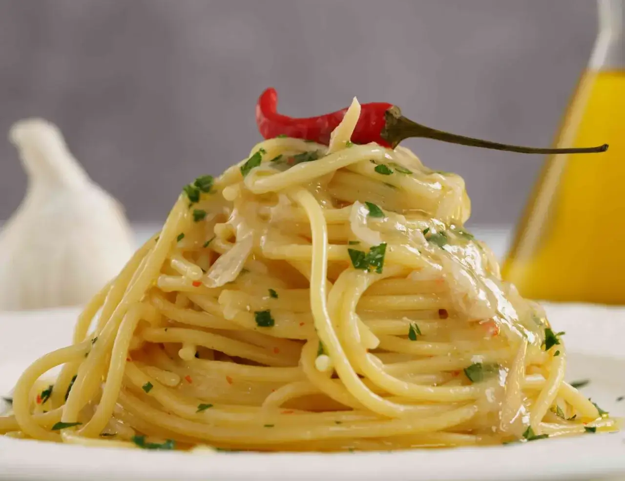 Un invitante piatto di pasta alla carrettiera, condita con aglio, olio, peperoncino e prezzemolo, guarnita con un peperoncino rosso.