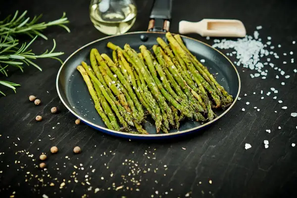 Asparagi in padella, conditi con sale e pepe, pronti per essere gustati.