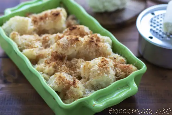 Cavolfiore al forno con pangrattato e formaggio, dorato e croccante, servito in una teglia verde brillante.