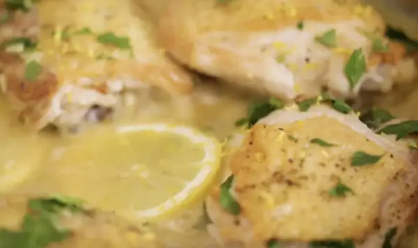 Succulento pollo al limone, dorato e profumato, con fette di limone e prezzemolo fresco.