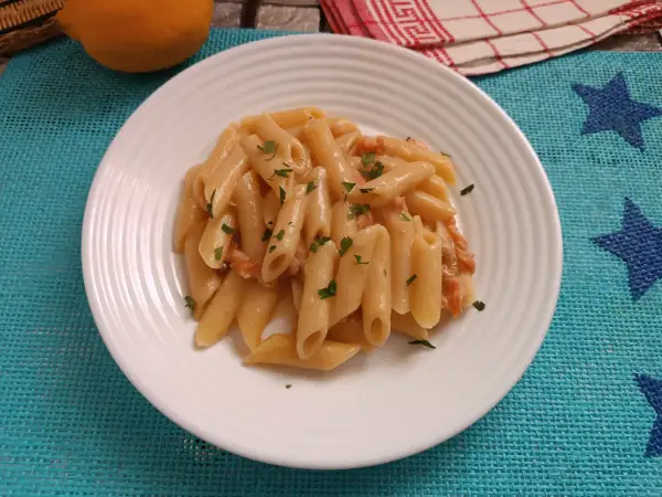 Piatto di pasta al salmone senza panna, guarnita con prezzemolo fresco. Un'opzione leggera e gustosa.