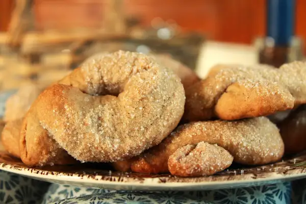 Ciambelline al vino dorate e cosparse di zucchero, un dolce profumato e croccante, perfetto per accompagnare un caffè.
