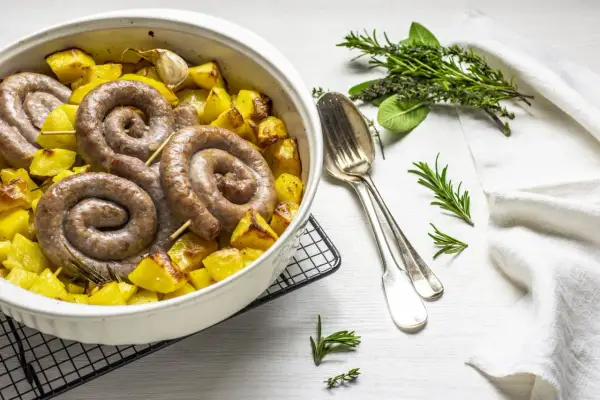 Salsiccia e patate al forno, un piatto rustico e saporito, con erbe aromatiche e aglio.