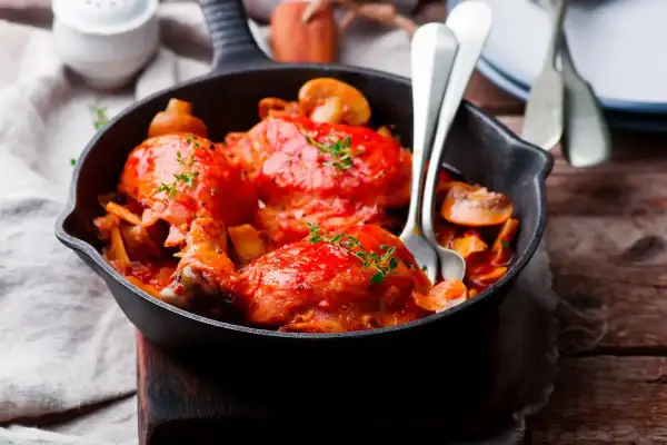 Pollo alla Marengo succulento in padella con funghi e pomodoro, guarnito con timo fresco.