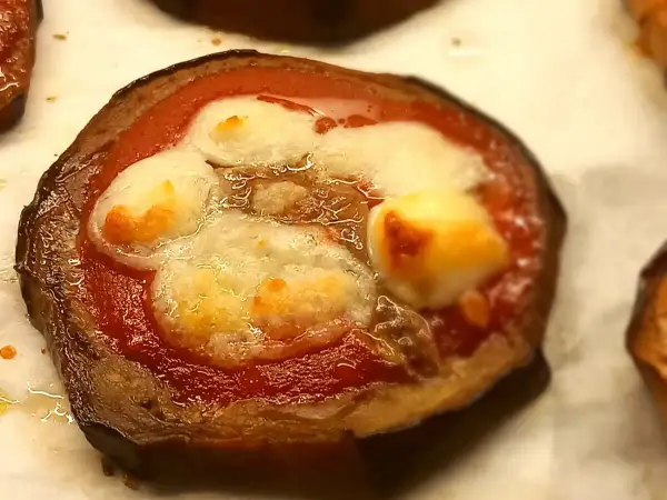 Pizzette di melanzane con pomodoro e mozzarella filante, un antipasto gustoso e leggero.