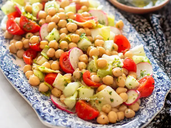 Insalata di ceci fresca e colorata con pomodorini, cetrioli e ravanelli, condita con erbe aromatiche.