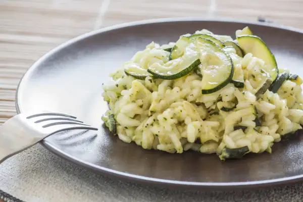 Un cremoso risotto con zucchine, guarnito con fette sottili di zucchine fresche, pronto per essere gustato.
