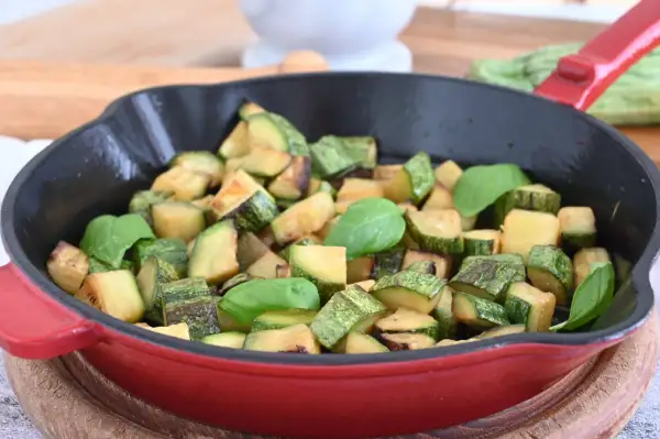 Zucchine in padella sfiziose, dorate e profumate, guarnite con foglie di basilico fresco. Un contorno semplice e gustoso.