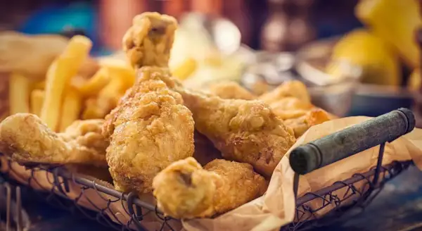 Cesto pieno di croccante petto di pollo impanato e patatine fritte dorate.