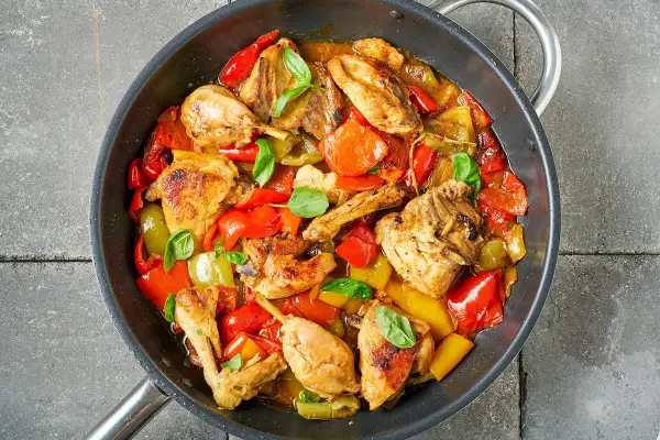 Pollo e peperoni in padella, un piatto colorato e saporito, con pezzi di pollo dorati e peperoni rossi e gialli cotti a puntino.