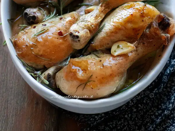 Succulente sovracosce di pollo al forno, dorate e profumate con aglio e rosmarino, servite in una ciotola bianca.