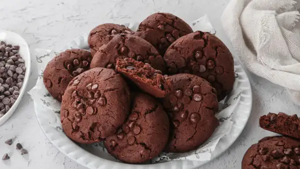 Un mucchio di deliziosi biscotti al cioccolato, perfetti per chi cerca biscotti senza burro. Alcuni sono interi, altri spezzati, rivelando un interno morbido e ricco.