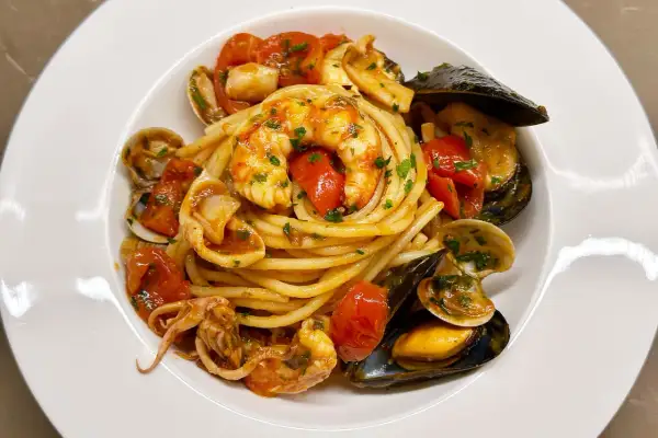 Un piatto invitante di spaghetti allo scoglio, con gamberi, cozze, vongole e calamari, condito con pomodorini e prezzemolo.