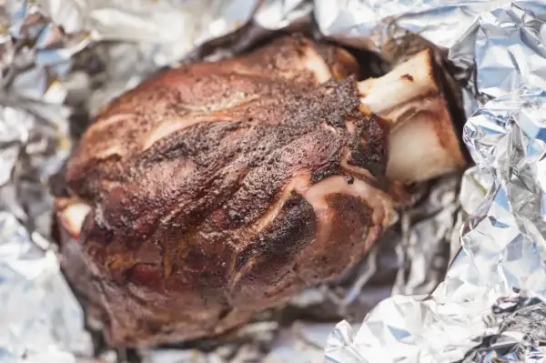Stinco di maiale succulento, cotto alla perfezione e avvolto in carta stagnola, pronto per essere gustato.