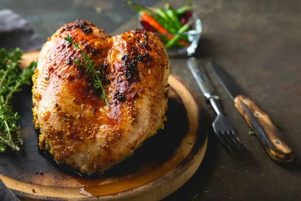 Petto di pollo al forno dorato e succulento, condito con senape e erbe aromatiche, pronto per essere gustato.