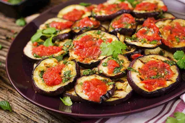Fette di melanzane grigliate condite con salsa di pomodoro e basilico, un classico piatto di melanzane alla pizzaiola.