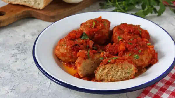 Polpette di pane succulente in salsa di pomodoro, guarnite con prezzemolo fresco. Un piatto casalingo che sa di tradizione.