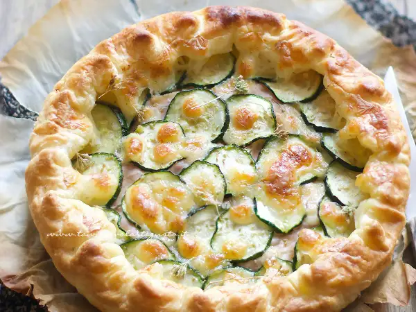 Torta salata con zucchine, formaggio filante e crosta dorata, pronta per essere gustata.