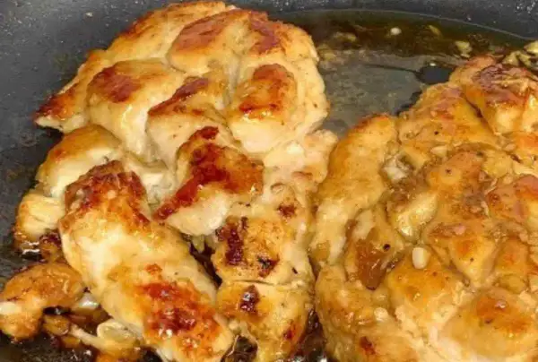 Succulento pollo in padella, dorato e saporito, con pezzetti di aglio che aggiungono un tocco in più.